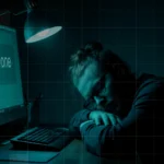 An IT admin sleeps on his desk in front of computer screen that says “Done”