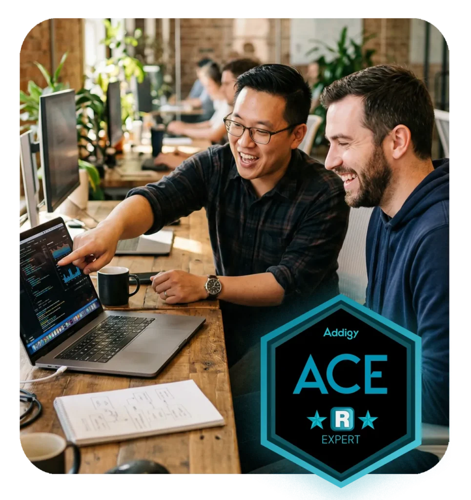 Two IT professionals laughing together in a modern office, Two IT professionals collaborating in a modern office, one pointing at a MacBook screen while a colleague listens and smiles