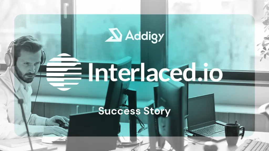 Bearded man wearing headphones works focused at a multi-monitor desktop workstation in a bright office, using a mouse. Interlaced and Addigy logo overlay