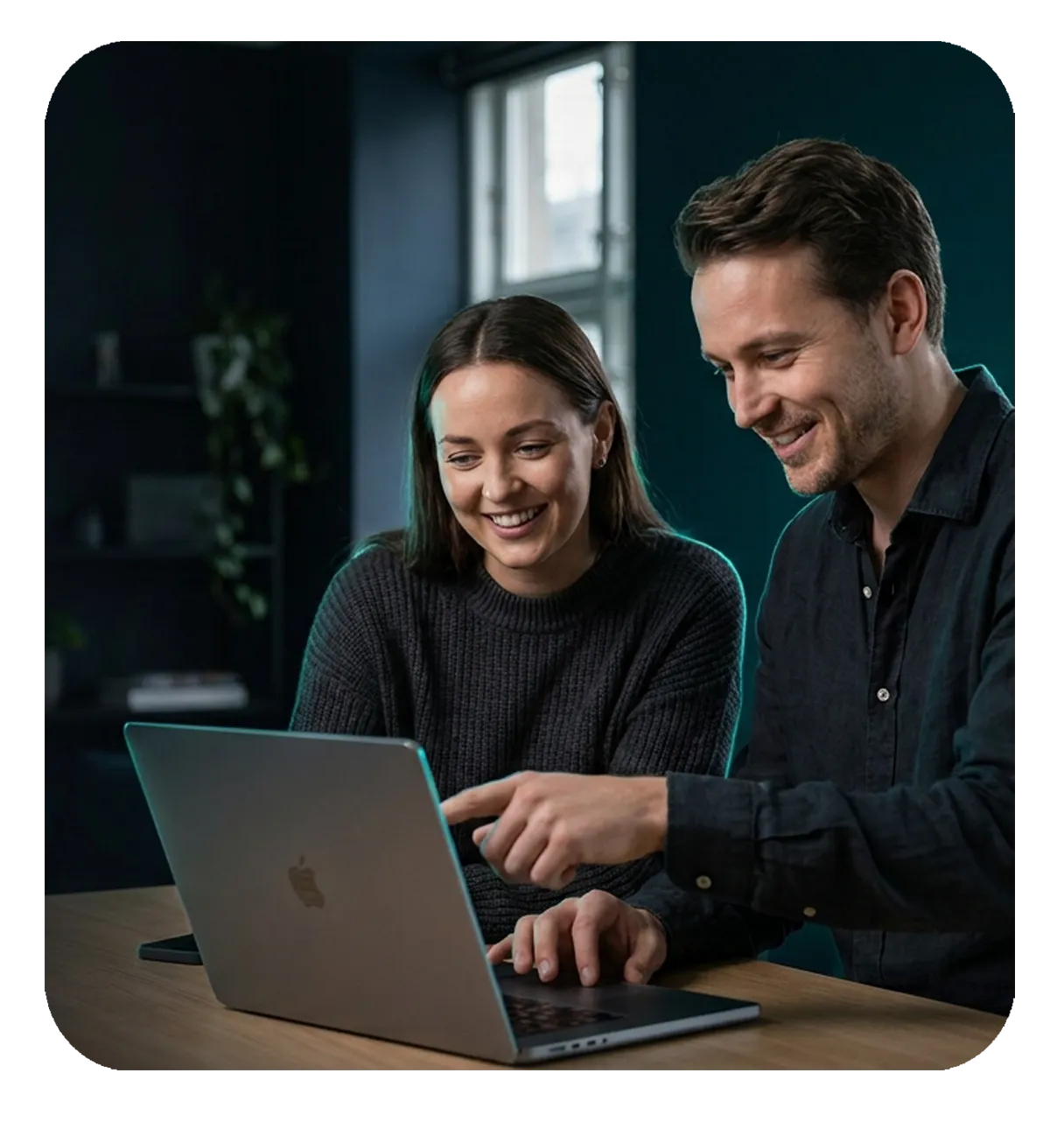Two IT professionals collaborating at a MacBook, reviewing Apple device management together